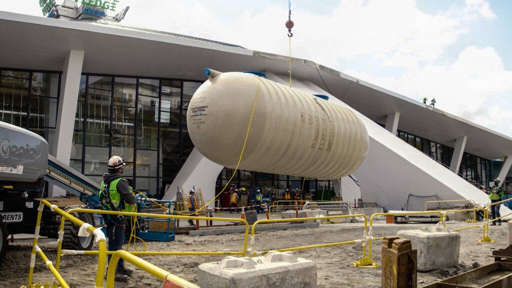 large white cistern suspended on a cable next to Climate Pledge Arena during construction
