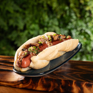 Sausage in bun on wood tray